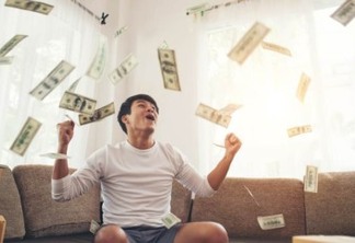 Happy man with cash dollars flying in home office, Rich from business online concept
