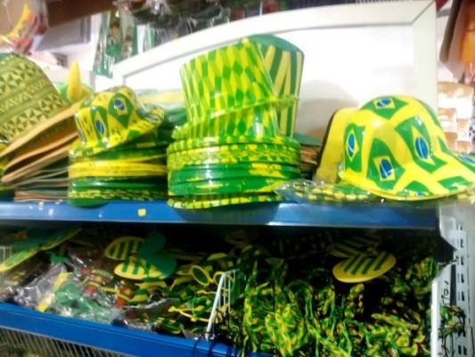 Chapéus verde e amarelo de vários modelos enfeitam as prateleiras das lojas.