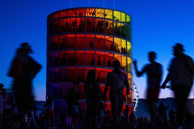 Festival-goers make their way through the grounds as silhouettes against...