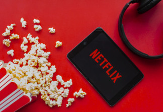 Calgary, Alberta. Canada. June 1 2020. An iPad with the Netflix logo on the screen on a red background with popcorn and headphones