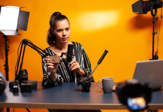 Influencer holding microphone while talking about her vlog equipment. Social media star making online internet content about video equipment for web subscribers and distribution, film